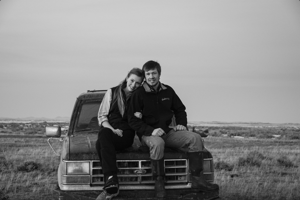 young couple sitting on old ranch vehicle, central montana family cattle ranch